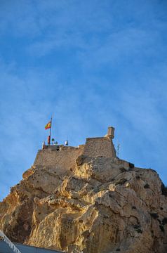Das Castillo de Santa Bárbara in Alicante auf einem felsigen Berg unter einem klaren blauen Himmel. von LuCreator