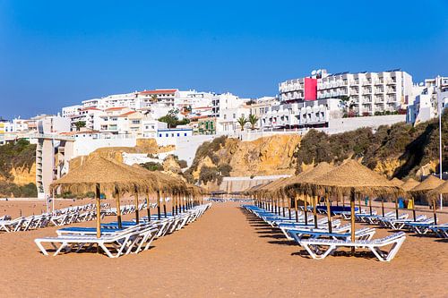 Rijen strandparasols met appartementen aan kust bij Albufeira in Portugal