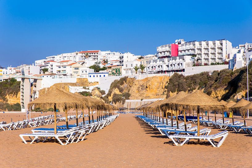 Reihen der Strandschirme mit Wohnungen auf Küste bei Albufeira in Portugal von Ben Schonewille