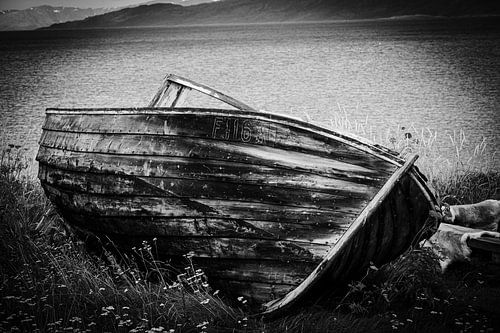 Zwart-wit foto van verlaten houten boot aan Noorse kust