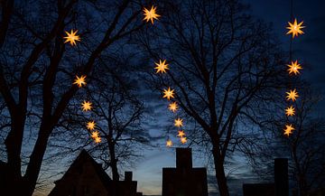 Verlichte Herrnhuter Moravische Kerststerren die boven de donkere silhouetten van oude huisgevels en van Maren Winter
