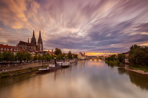 Blick über Regensburg mit Dom, Salzstadel und Steinerner Brücke am Abend mit ziehenden Wolken