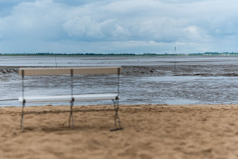 A bench stands in front of the Wadden Sea with a beautiful view by Matthias Korn
