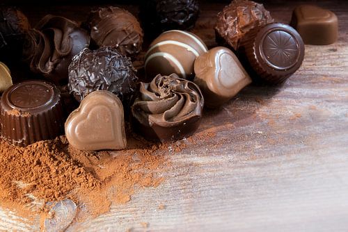 Fijne chocoladepralines op cacaopoeder als liefdesgeschenk, hoekachtergrond met kopieerruimte op rus