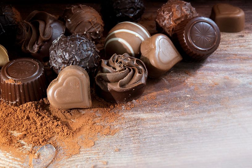 Fijne chocoladepralines op cacaopoeder als liefdesgeschenk, hoekachtergrond met kopieerruimte op rus van Maren Winter