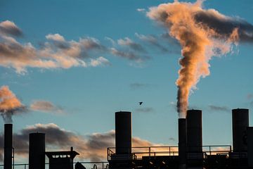 Rokende schoorstenen van een fabriek in de ondergaande zon van ManfredFotos
