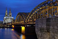 Cologne Cathedral and Hohenzollern Bridge at night.