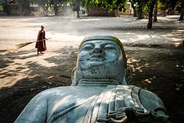 Monk balaie un carré propre où une grande statue de Bouddha se trouve. La photo a été prise dans la 
