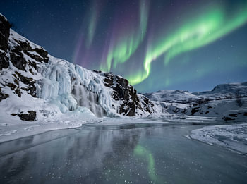 Aurora Borealis Over Frozen Waterfall in Winter Landscape