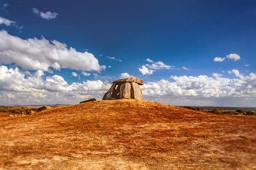 Dolmen préhistorique sous un ciel bleu vibrant avec des nuages. Tombe mégalithique dans l'Alentejo, au Portugal.
