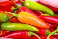 Ein Haufen scharfer roter, orangefarbener und grüner Chilischoten für scharfes Essen