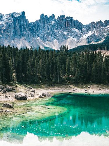 Lago di Carezza (Karersee) blue lake with pine trees and the peaks of the Dolomites