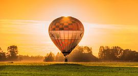Hot air balloon in the evening light of the setting sun by Harrie Muis