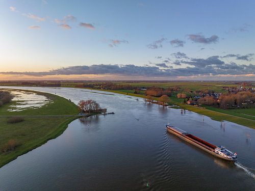 Vrachtschip varend op de IJssel met hoog water