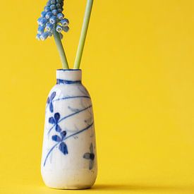 Klein chinees antiek vaasje met twee blauwe druifjes op gele achtergrond. van Marjolein Hameleers
