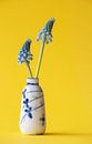 Klein chinees antiek vaasje met twee blauwe druifjes op gele achtergrond. van Marjolein Hameleers thumbnail