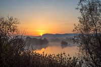 Sonnenaufgang über Hügeln an einem Fluss
