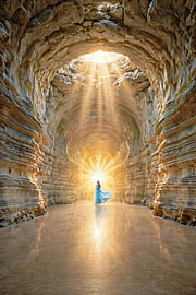 Licht am Ende des Tunnels – Frau in blauem Kleid in einer Mergelhöhle mit Sonnenstrahlen von Henk Egbertzen