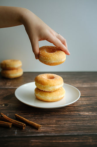 Sugared Doughnut Held over a Plate