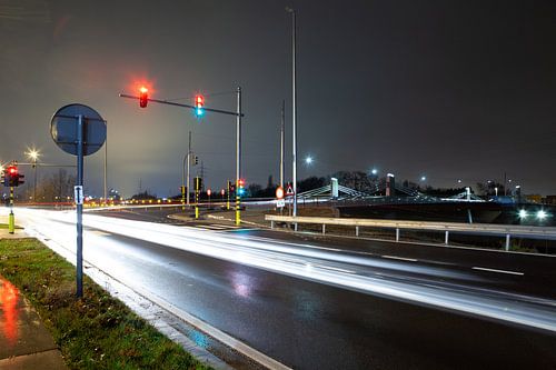 Brug met drukke straat en verkeerslichten 's nachts