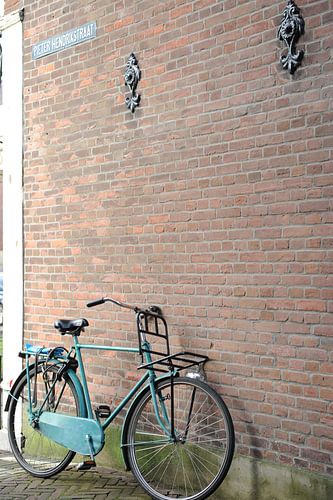 Blauwe herenfiets met voordrager tegen muur Delft