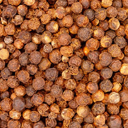 Hele zwarte peperkorrels met rustieke textuur en kookingrediënt