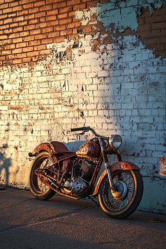 Oude roestige motorfiets tegen muur