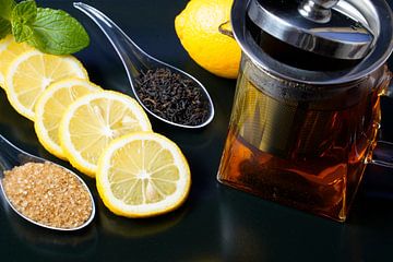 Thé noir servi avec des tranches de citron, du sucre et une théière