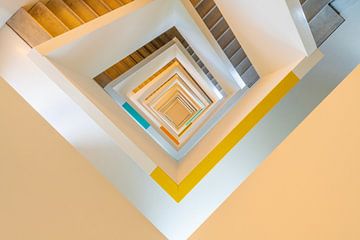 Naar beneden kijken naar een kleurrijk trappenhuis van Bob Janssen
