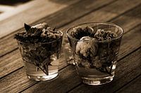 Schöne frische gemischte Blumen in Glasvasen auf einem Holztisch in Sepia angeordnet.