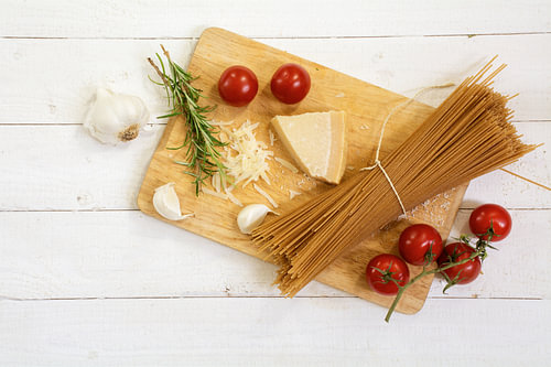 Küchentafel mit Zutaten für eine italienische Mahlzeit von oben gesehen mit Vollkornspaghetti, Tomat