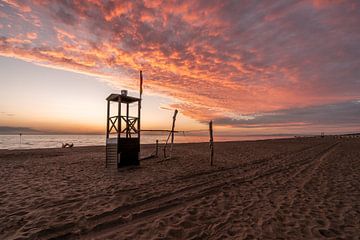 Kleurrijke zonsondergang met houten strandhuis van Dafne Vos