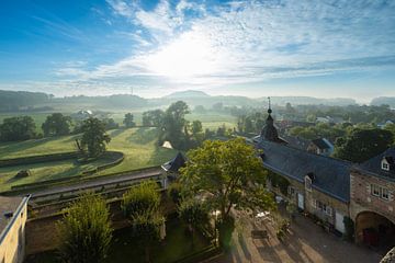 autumn morning seen over the Jeker valley and Chateau Neercanne with mist and sun harps by Kim Willems