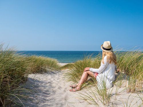 Jonge vrouw zittend in de duinen op Sylt aan de Noordzee