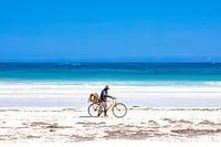 Tropisch wit strand met azuurblauwe zee en blauwe lucht en een fietser