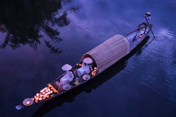 Lighting candles in baskets on the river by Anges van der Logt