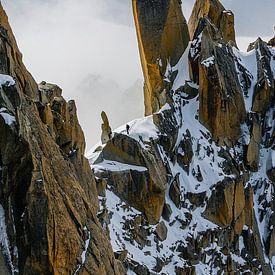Lonely mountaineer between clouds, snow and rocks by Bep van Pelt- Verkuil