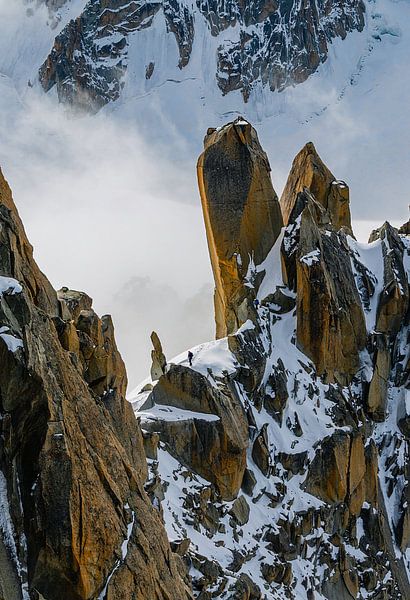 Lonely mountaineer between clouds, snow and rocks by Bep van Pelt- Verkuil