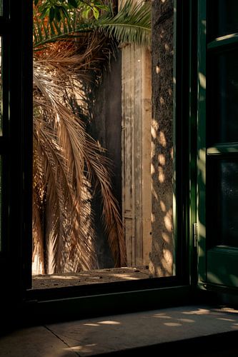 Blick auf einen sonnenbeschienenen Innenhof durch ein Fenster in Catania, Italien
