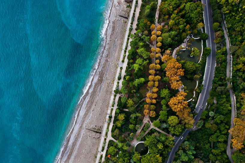 Ruelle avec des arbres et une route. Hôtels parmi le parc vert en bord de mer avec une eau turquoise par Michael Semenov
