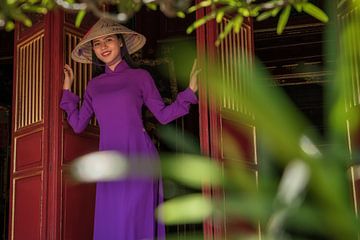 A Vietnamese woman in purple clothes emerges from the door of the temple by Anges van der Logt