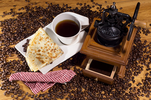 Coffee with an old coffee grinder and pastries on a wooden table