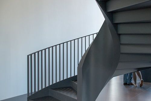 Spiraaltrap waaronder twee paar voeten te zien zijn, 1 paar van een mannelijk figuur en 1 paar voeten van een verlegen meisje.