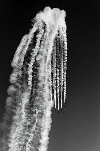 Luchtshow met vliegend eskader en rook in bewolkte hemel in zwart-wit