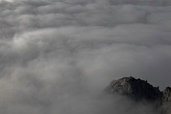 Peak of mountain surrounded by clouds.