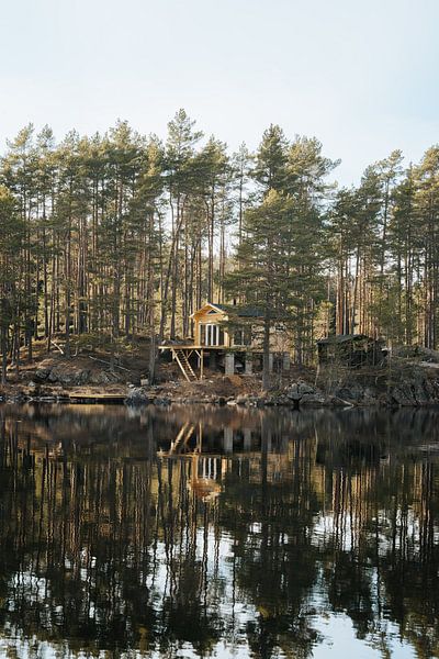 Cabin by reflecting lake at sunset in Sweden by Joep van de Zandt