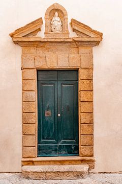 Blue wooden door with stone statue of Mary by Dafne Vos