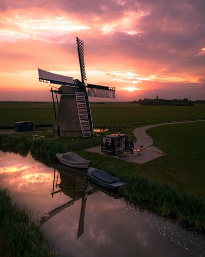 Camper bij molen tijdens zonsondergang