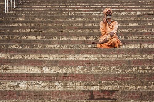 man rust op stappen van een ghat in Varanasi, India.