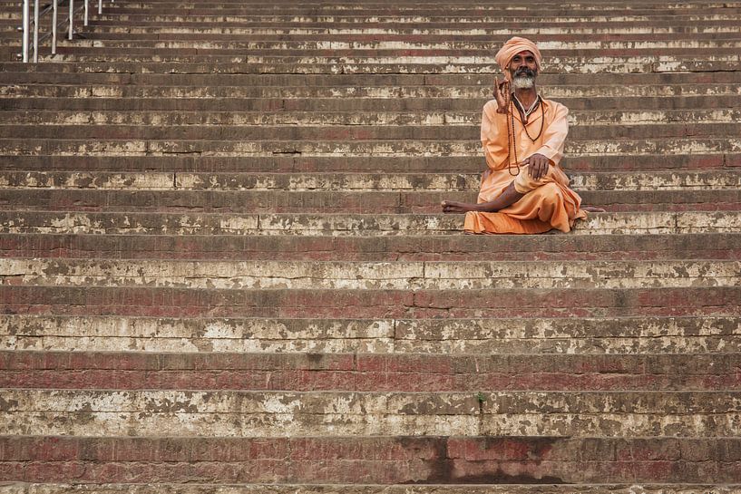 man rests on steps of a ghat in Varanasi, India. by Tjeerd Kruse